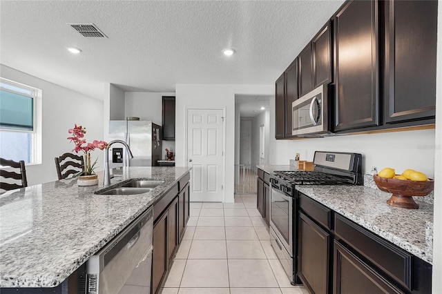 kitchen featuring stainless steel appliances, a sink, light stone counters, and light tile patterned floors