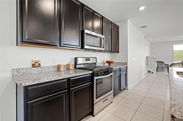 kitchen with light tile patterned floors, visible vents, appliances with stainless steel finishes, open floor plan, and a textured ceiling