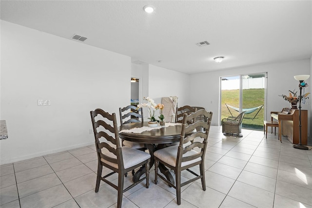 dining space with visible vents, a textured ceiling, baseboards, and light tile patterned floors