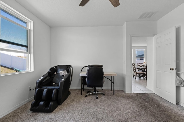 carpeted office space featuring baseboards, plenty of natural light, visible vents, and a textured ceiling