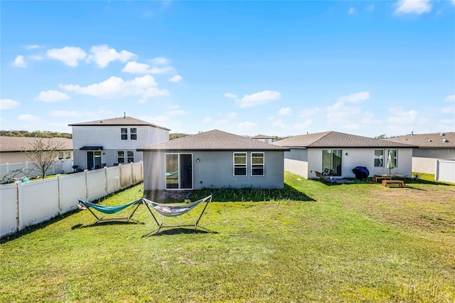 back of property featuring a lawn, a fenced backyard, and stucco siding