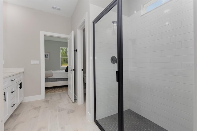 ensuite bathroom featuring connected bathroom, wood finished floors, vanity, visible vents, and a stall shower