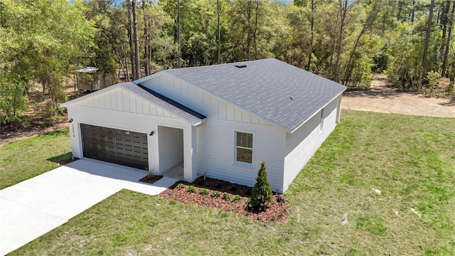exterior space featuring board and batten siding, driveway, a front yard, roof with shingles, and an attached garage