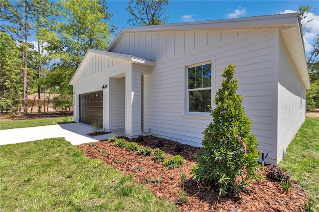 view of property exterior with a yard, board and batten siding, an attached garage, and driveway