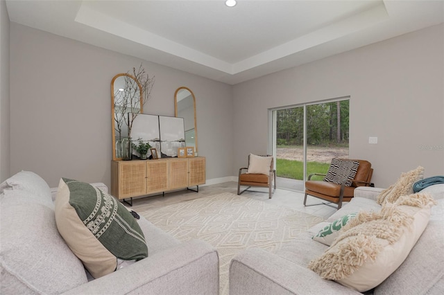 living room featuring a raised ceiling, baseboards, and recessed lighting