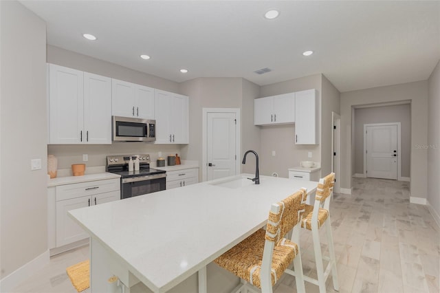 kitchen with light countertops, white cabinets, appliances with stainless steel finishes, and a sink