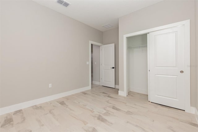 unfurnished bedroom featuring baseboards, a closet, light wood finished floors, and visible vents