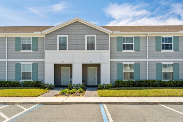 townhome / multi-family property featuring uncovered parking and a front lawn