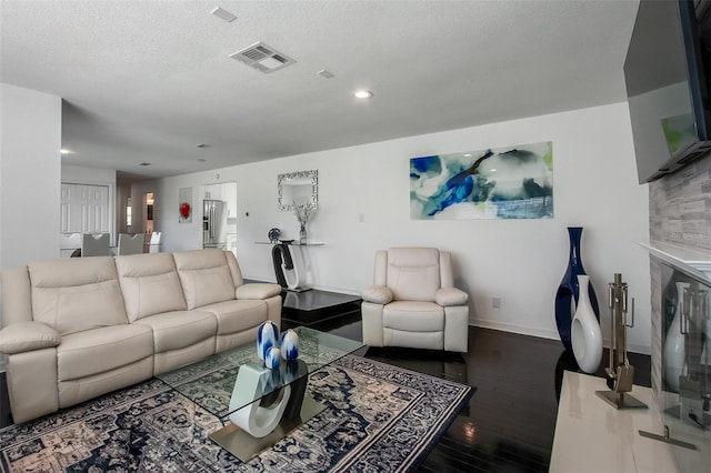 living room with dark wood finished floors, recessed lighting, visible vents, a textured ceiling, and baseboards