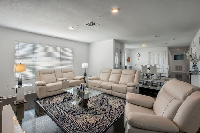 living area with visible vents, a textured ceiling, baseboards, and wood finished floors