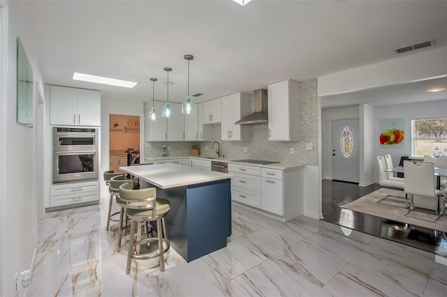 kitchen featuring marble finish floor, wall chimney exhaust hood, tasteful backsplash, and stainless steel appliances