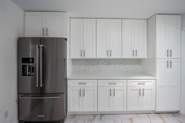 kitchen featuring light countertops, high end refrigerator, backsplash, and white cabinets