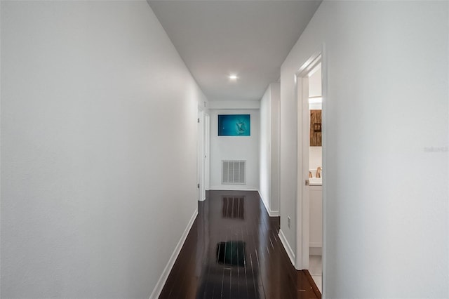 corridor featuring dark wood-style flooring, visible vents, and baseboards