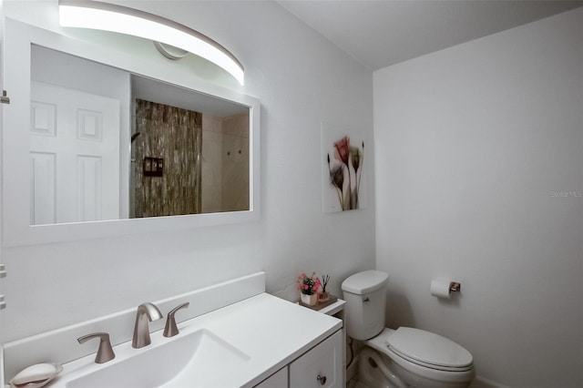 bathroom featuring a tile shower, vanity, and toilet