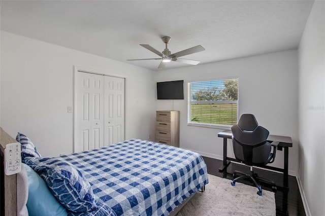 bedroom featuring a ceiling fan, a closet, baseboards, and wood finished floors