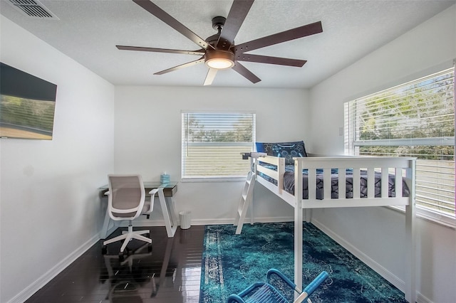 bedroom with visible vents, ceiling fan, a textured ceiling, wood finished floors, and baseboards