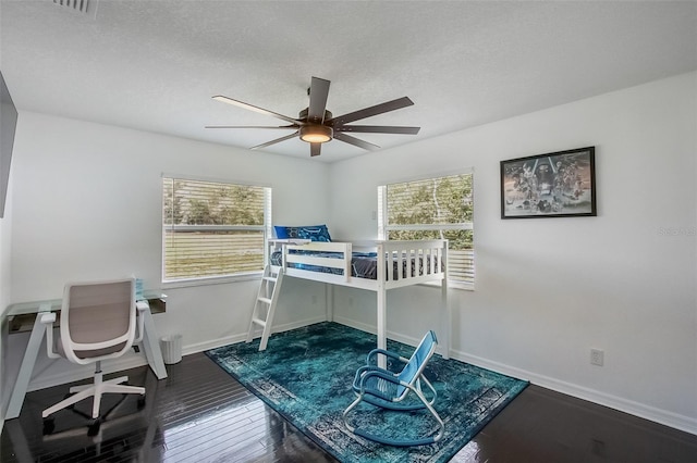 bedroom featuring a ceiling fan, wood-type flooring, baseboards, and a textured ceiling