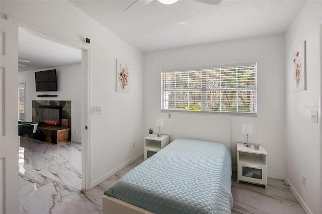 bedroom featuring marble finish floor, ceiling fan, a fireplace, and baseboards