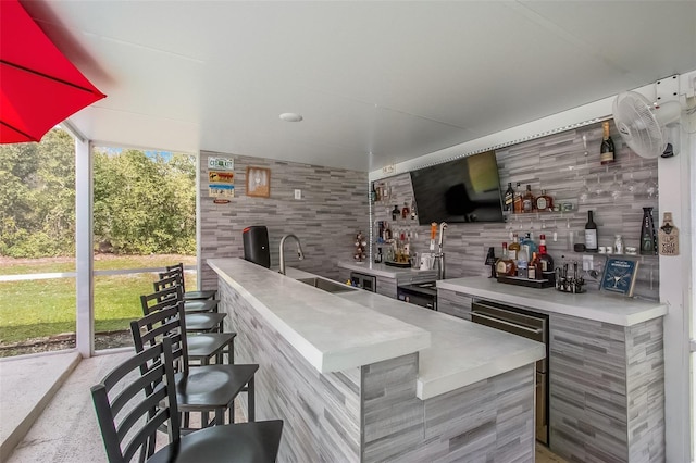 bar with decorative backsplash, indoor wet bar, and a sink