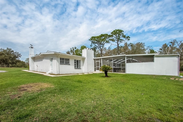 back of house with stucco siding, a chimney, and a yard