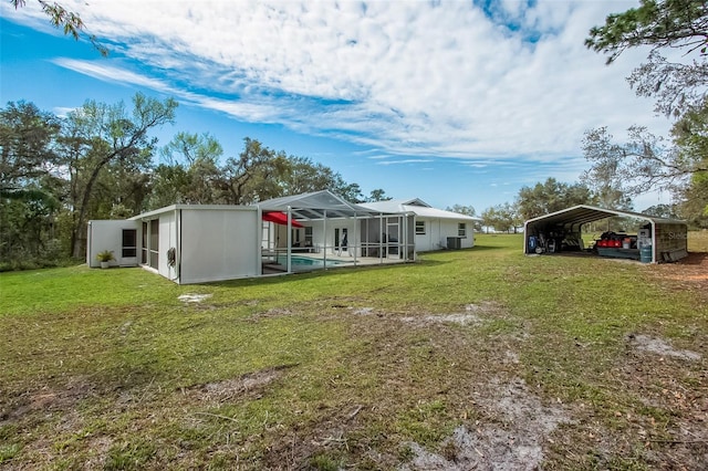 back of house featuring a pool, a detached carport, a lawn, glass enclosure, and driveway