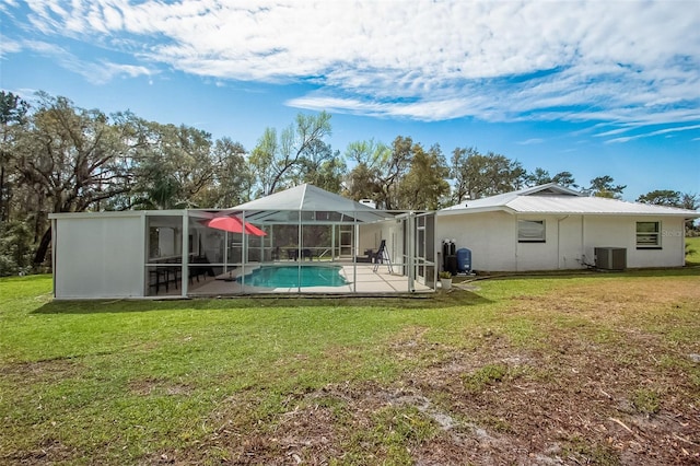 back of property featuring glass enclosure, a patio, cooling unit, a lawn, and an outdoor pool