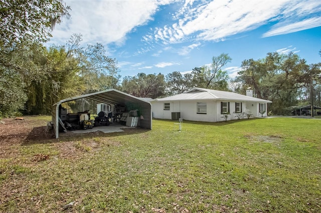 rear view of property with a carport, a chimney, a yard, and driveway