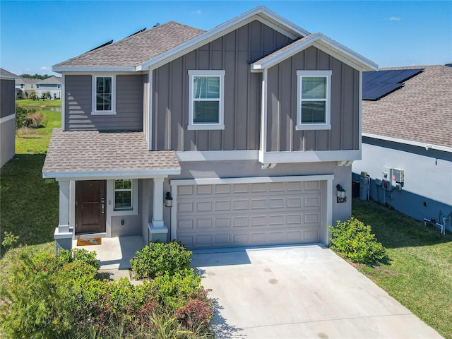 view of front of home with a garage, concrete driveway, roof with shingles, board and batten siding, and a front yard