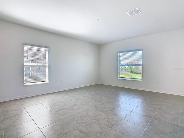 tiled spare room featuring baseboards and visible vents