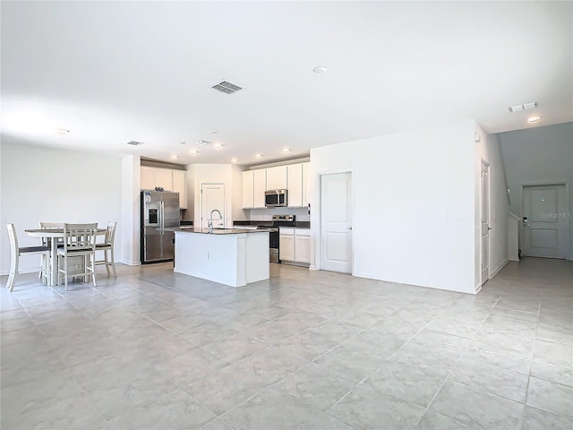 kitchen with appliances with stainless steel finishes, dark countertops, visible vents, and a sink