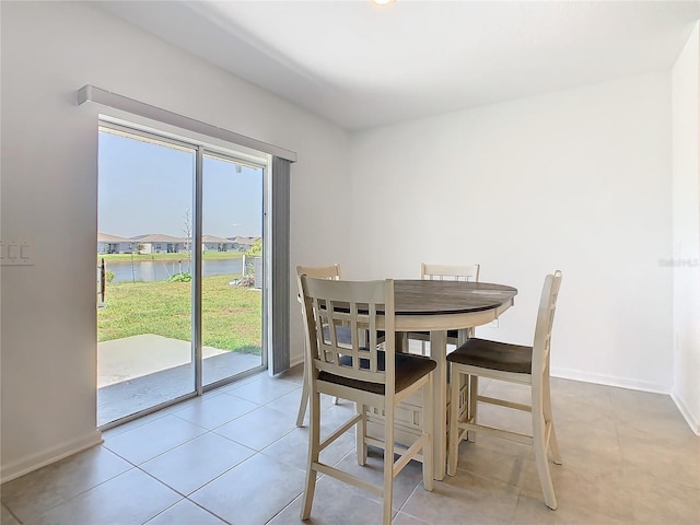 dining area with a water view, baseboards, and light tile patterned floors