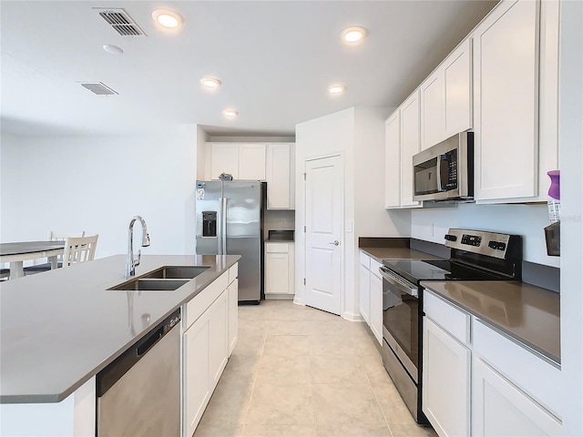 kitchen featuring dark countertops, visible vents, stainless steel appliances, and a sink