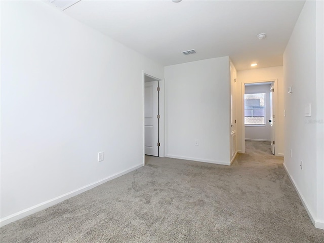 carpeted spare room with visible vents and baseboards