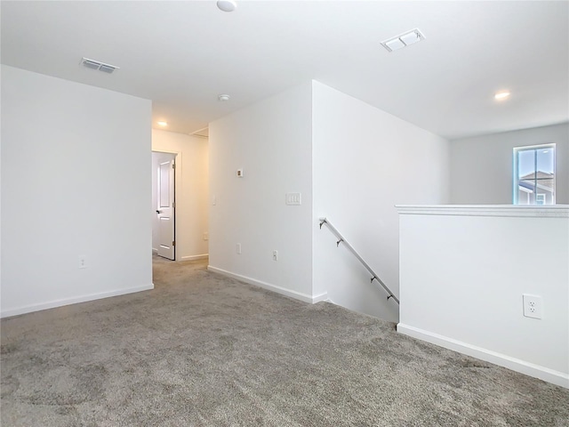 spare room featuring carpet floors, visible vents, and baseboards