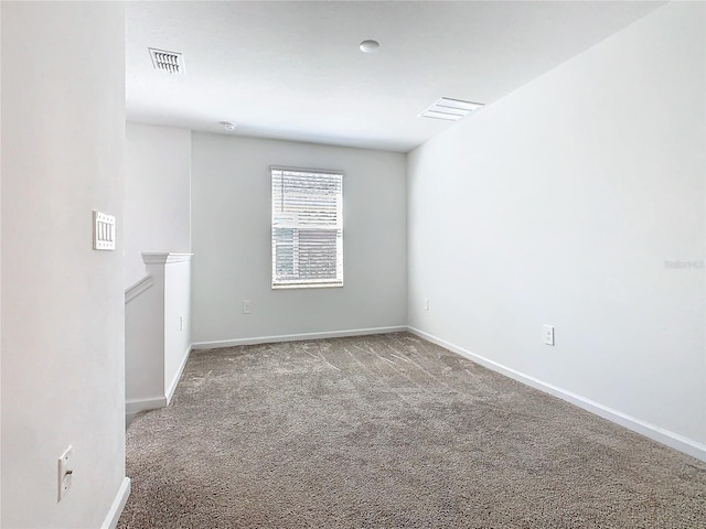 empty room with carpet, visible vents, and baseboards