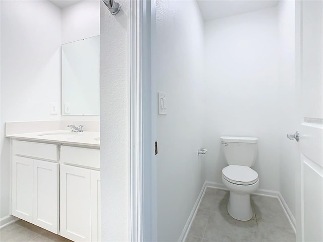 bathroom with tile patterned flooring, baseboards, vanity, and toilet