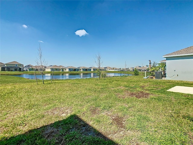 view of yard with a water view, central air condition unit, and a residential view