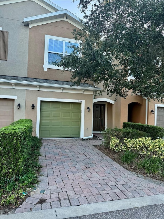 townhome / multi-family property featuring decorative driveway, an attached garage, and stucco siding