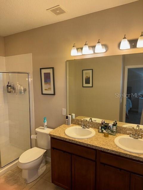 full bath with tile patterned flooring, visible vents, a sink, and a shower stall