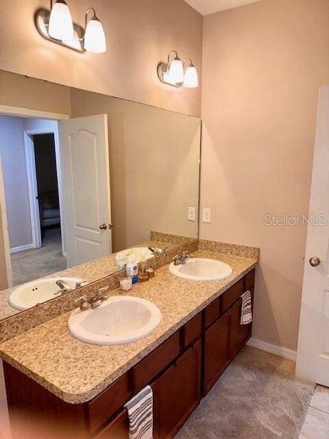 bathroom featuring double vanity, baseboards, and a sink