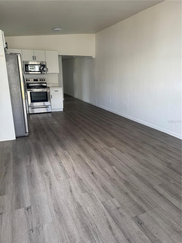 kitchen with dark wood finished floors, open floor plan, stainless steel appliances, light countertops, and white cabinetry