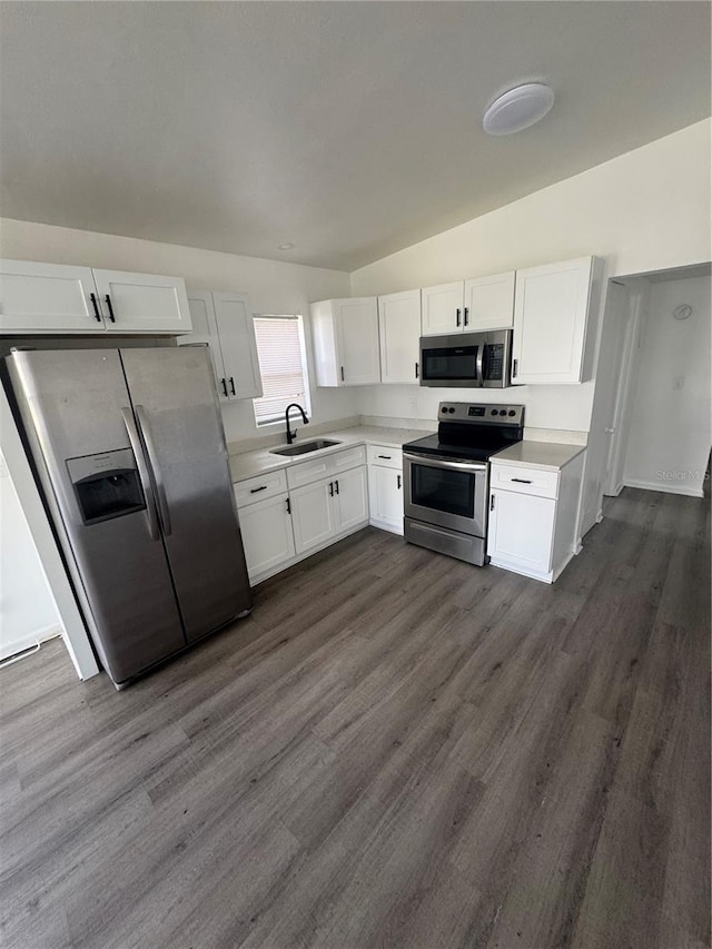 kitchen with stainless steel appliances, a sink, white cabinets, light countertops, and dark wood-style floors