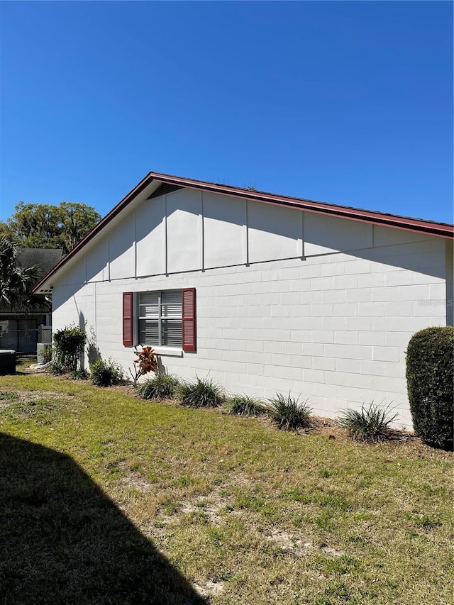 view of home's exterior with concrete block siding and a lawn