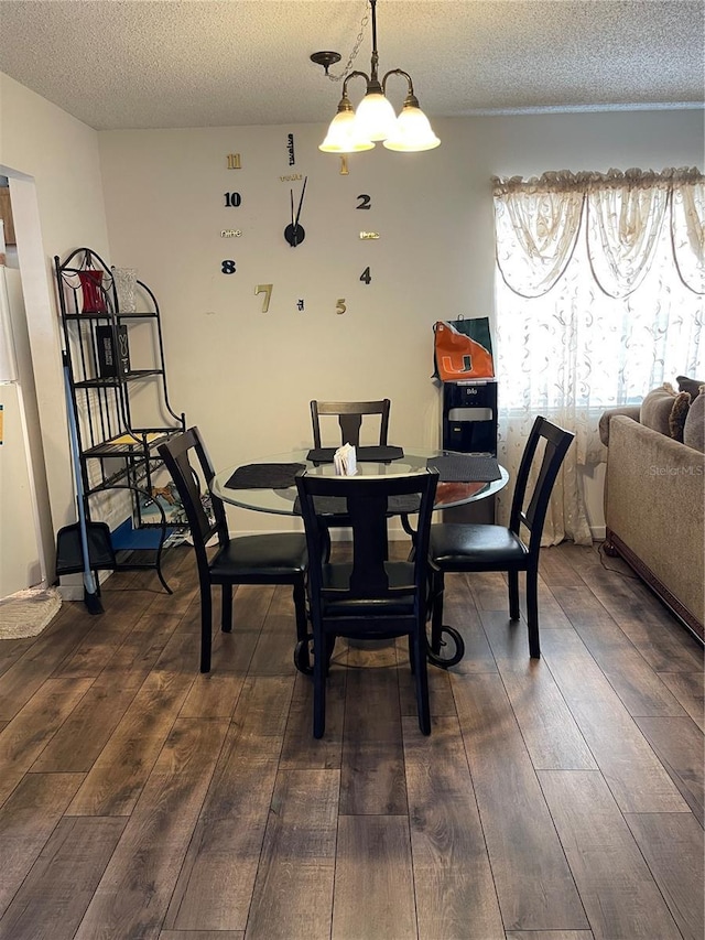 dining area with a notable chandelier, a textured ceiling, and dark wood finished floors