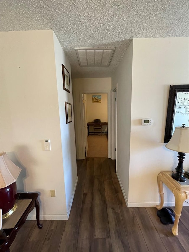 corridor with visible vents, a textured ceiling, baseboards, and wood-type flooring