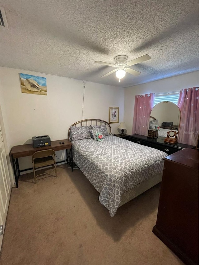 bedroom featuring light colored carpet, ceiling fan, and a textured ceiling