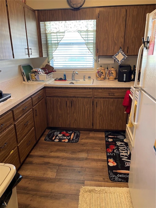 kitchen with a sink, dark wood-style floors, light countertops, and freestanding refrigerator