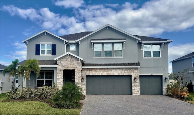 view of front of house with stucco siding, decorative driveway, stone siding, roof with shingles, and an attached garage