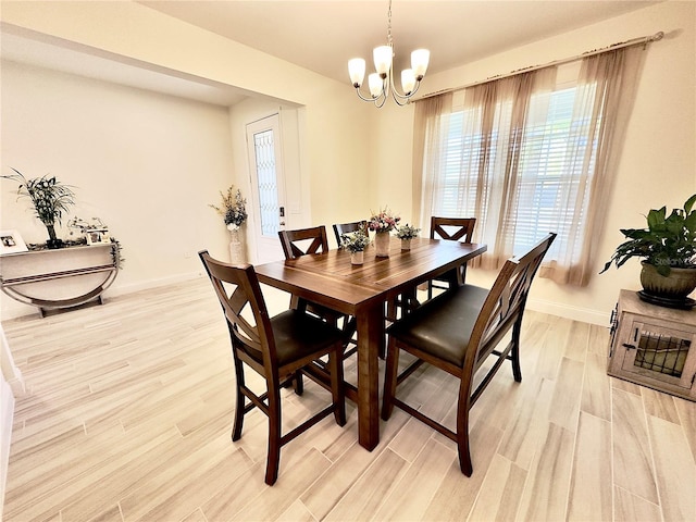 dining area featuring a chandelier, light wood-type flooring, and baseboards