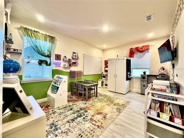 playroom with wood finished floors, visible vents, and baseboards